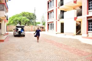 基苏木Bomani Penthouse的一位妇女沿着车旁的街道走