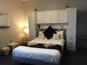 曼彻斯特曼彻斯特皇后旅馆的一间卧室配有一张带白色橱柜的大床