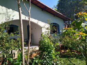 戈亚斯州上帕莱索Casa dos Buritis-no centro turístico的花园内带蓝色窗户的白色小房子