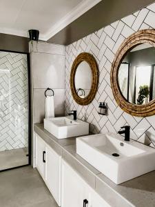 比勒陀利亚Battiss Guest House的白色的浴室设有两个盥洗盆和镜子