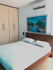 巴兰基亚Hotel Suites Caribe的卧室配有一张白色大床,墙上挂有绘画作品