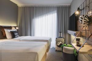 洛桑Moxy Lausanne City的酒店客房设有两张床和窗户。