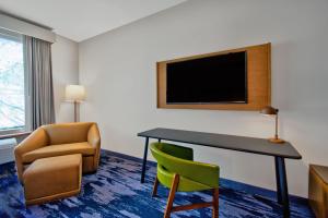 奥兰多Fairfield by Marriott Inn & Suites Orlando at FLAMINGO CROSSINGS® Town Center的酒店客房配有书桌、椅子和电视。