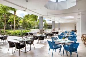 Avon ParkLe Méridien Dania Beach at Fort Lauderdale Airport的一间设有桌椅的餐厅,种植了棕榈树