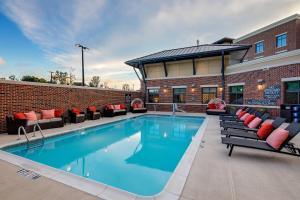 萨默维尔Residence Inn by Marriott Charleston Summerville的砖砌建筑旁的一个带沙发和椅子的游泳池
