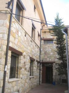 BarahonaHostal Guarni的一座石头建筑,旁边有一扇门和一棵树
