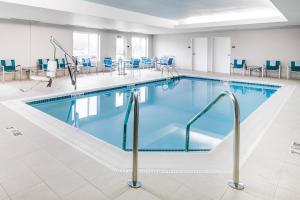 堪萨斯城TownePlace Suites by Marriott Kansas City Airport的大楼内一个带蓝色桌椅的游泳池