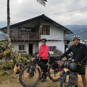 莫科阿Hostal de la montaña ecoturismo的一位男人和女人,在房子前面骑着自行车