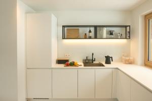 拉瓦莱Ciasa Plandros Apartments的厨房配有白色橱柜和水槽