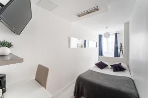 巴黎L'Oasis Montparnasse的白色客房 - 带一张带紫色枕头的床