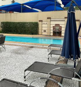 圣保罗Sao Paulo Ibirapuera Privilege - Suite Deluxe的一个带椅子和蓝伞的游泳池