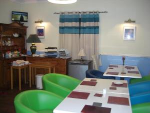 卡莱尔Lynebank House Hotel, Bed & Breakfast的一间设有两张桌子和绿色椅子的房间