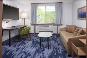 格林菲尔德Fairfield Inn & Suites by Marriott Indianapolis Greenfield的一间客厅,客厅配有沙发和一张书桌,位于酒店的房间