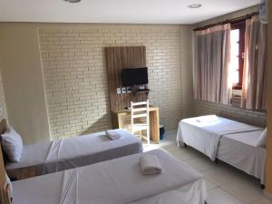 戈亚尼亚Rede Andrade Goiania Centro的酒店客房设有两张床和电视。