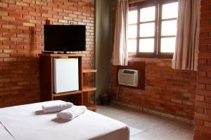 戈亚尼亚Rede Andrade Goiania Centro的一间卧室设有床铺、电视和砖墙