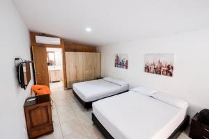 麦德林Medellin Backpacker Hostel的小房间设有两张床和电视