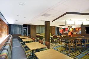 列治文山Fairfield Inn & Suites by Marriott Savannah SW/Richmond Hill的一间带木桌椅的餐厅和一间酒吧