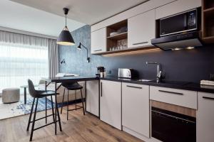 斯特拉斯堡Residence Inn by Marriott Strasbourg的厨房配有白色橱柜和桌椅