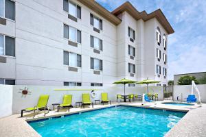 皮奥里亚凤凰城格伦代尔/皮奥里亚春季山丘套房酒店的酒店前的游泳池配有椅子和遮阳伞