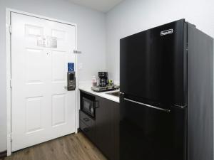 钱诺夫Studio 6 Channelview TX Baytown West的厨房配有黑色冰箱和白色门