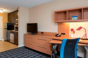波蒂奇TownePlace Suites by Marriott Kalamazoo的客房配有书桌、电视和书桌、四柱床和四柱床。