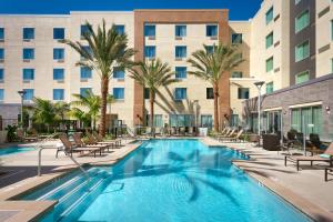 霍桑Courtyard by Marriott Los Angeles LAX/Hawthorne的酒店前方的游泳池设有椅子和棕榈树