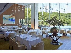 SaikaiOliveBay Hotel的餐厅设有白色的桌椅和大窗户