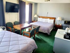 Monte VistaMonte Villa Hotel的酒店客房带两张床和一张桌子以及椅子。