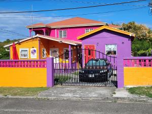OsbournTequila Sunrise Antigua的一座色彩缤纷的房屋,前面设有围栏
