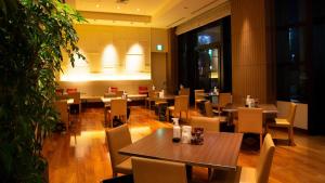 富山富山奥克斯运河公园酒店的一间设有木桌和椅子的餐厅,以及一座大型植物
