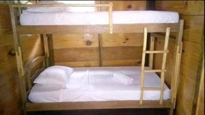 圣玛尔塔Cabaña Altos de San Carlos的两张双层床,配有白色床单和梯子