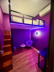 新加坡Arena eSports Hotel @ Bugis Village的一间客房配有一张带紫色墙壁的双层床。