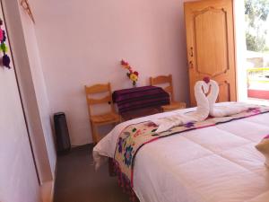 奥科苏尤Amantani Pachatata Lodge的一间卧室配有一张带两个天鹅的床