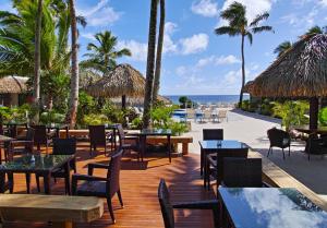 拉罗汤加Club Raro Resort- Adults Only的海滩上的餐厅,配有桌椅