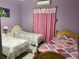 拉班达Hermosa Casa con Quincho y pileta的一间卧室配有两张床和粉红色窗帘