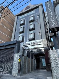 东京HOTEL REFRAIN的一座高大的灰色建筑,前面有标志