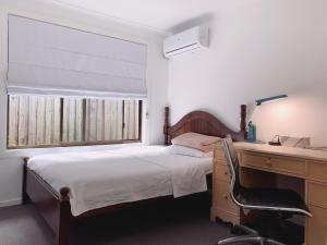 黄金海岸Home Away From Home-(Room1&2)的一间卧室配有书桌和一张带桌椅的床。