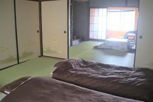 Sukumoゲストハウスさくら Guesthouse Sakura的一间卧室配有一张床,另一间卧室配有镜子