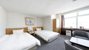 旭川Tabist THE GREEN ASAHIKAWA的酒店客房,配有两张床和椅子