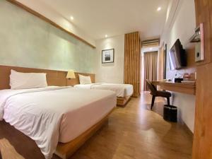 金巴兰Liberta Hotel Jimbaran的酒店客房配有两张床和一张书桌