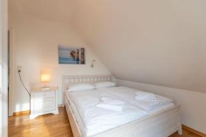 KarninFerienhaus Karnin B的卧室配有白色的床和床头柜