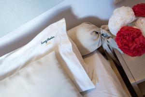 蒂锡利维Sunny Garden Hotel的一件带弓的白色连衣裙和两朵红玫瑰