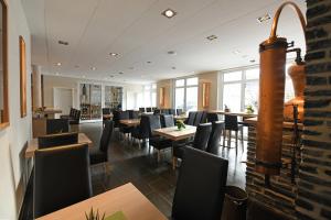 LonguichWeingut Heinen的餐厅设有黑椅子和桌子以及窗户。