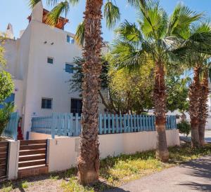 厄尔·坎皮洛·德·罗达尔Casa Appaloosa Cabo de Gata的两棵棕榈树和一根蓝色的围栏,在一座建筑前