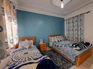 丹吉尔Diafa的卧室设有两张床铺和蓝色的墙壁