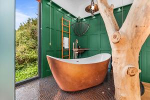 南安普敦Ivy Cottage Holiday Cabins的带浴缸的浴室和角落的树
