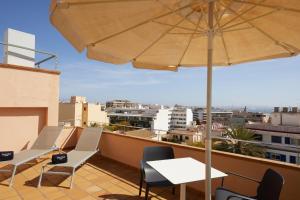 马略卡岛帕尔马Sercotel Hotel Zurbarán Palma的阳台配有桌椅和雨伞。