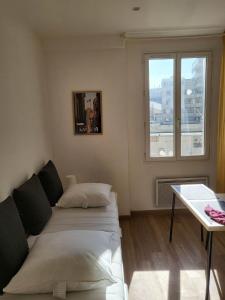 土伦Studio sur le port de Toulon的一间卧室配有一张床、一张桌子和一个窗户。