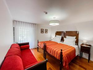 Fajã de Santo AmaroQuinta dos Mistérios- Turismo de Habitação的一间卧室配有一张床和一张红色的沙发