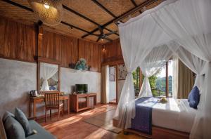 德格拉朗Sacred Valley by Pramana Villas的一间卧室配有一张带窗帘的床和一张书桌